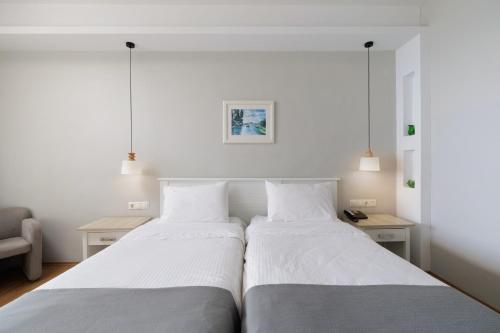 two beds in a bedroom with white walls at Elea Beach Hotel in Dassia