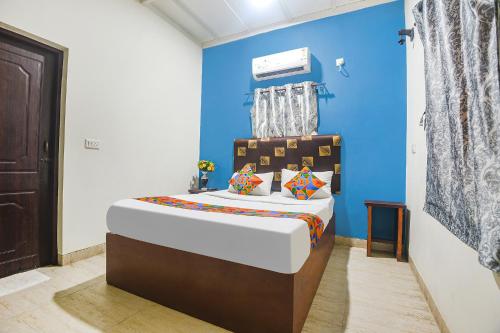 a bedroom with a bed with a blue wall at FabExpress IRAA Resort in Baga