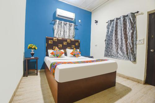 a bedroom with a bed with a blue wall at FabExpress IRAA Resort in Baga