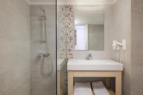 uma casa de banho com um lavatório e um chuveiro com um espelho. em Elea Beach Hotel em Dassia