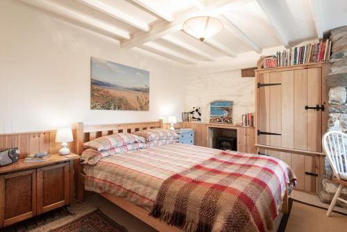 ein Schlafzimmer mit einem Bett, einem Tisch und einem Stuhl in der Unterkunft Traditional stone cottage with sea views in Snowdonia National Park in Brynkir
