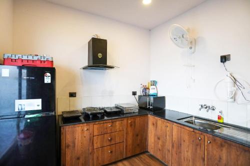 a kitchen with wooden cabinets and a black refrigerator at Ekta Houseboat Statue Of Unity Kevadia in Vadodara