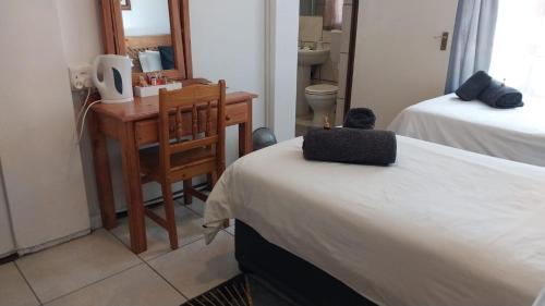 a room with two beds and a desk and a chair at Lily Guesthouse in Bloemfontein