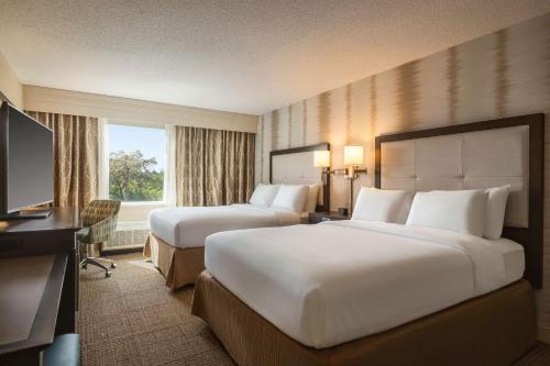 a hotel room with two beds and a desk and a television at Hampton Inn Pembroke Pines in Pembroke Pines