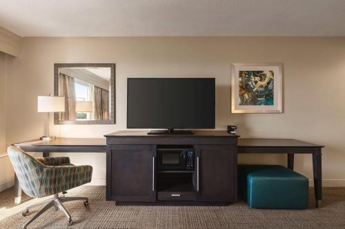 a room with a desk with a television and a chair at Hampton Inn Pembroke Pines in Pembroke Pines