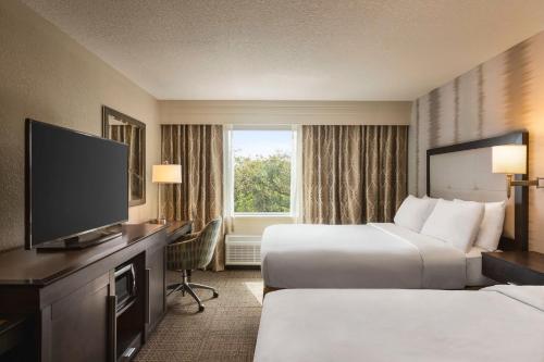 a hotel room with two beds and a flat screen tv at Hampton Inn Pembroke Pines in Pembroke Pines
