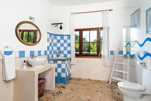 a bathroom with a sink and a toilet and a mirror at Villa Son Prats in Cala Santandria