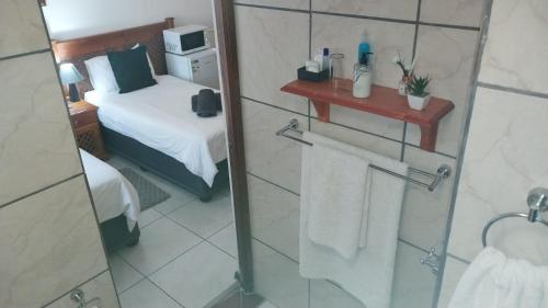 a bathroom with a shower with a bed and a mirror at Lily Guesthouse in Bloemfontein
