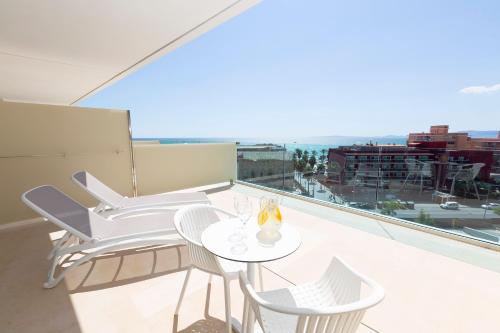 uma mesa branca e cadeiras numa varanda com vista em Hipotels Gran Playa de Palma em Playa de Palma