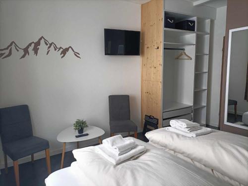 two beds in a room with two chairs and a mirror at Pension & Ferienwohnungen Haus Edelweiß in Holzgau