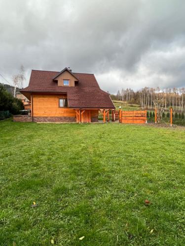 een huis in een veld met een groene tuin bij Highlander - drewniany dom w Beskidach in Kamesznica