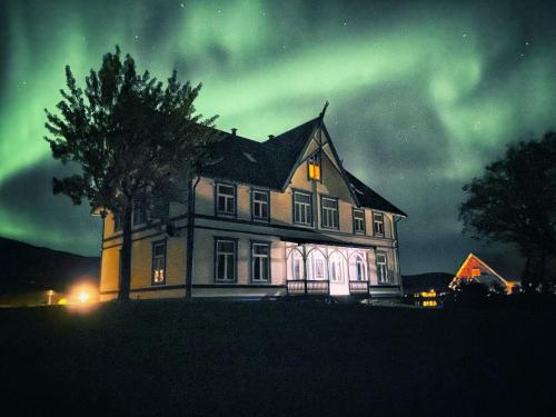 Ein altes Haus, in dem nachts die Aurora aufgeht in der Unterkunft Sandtorgholmen Hotel - Best Western Signature Collection in Harstad