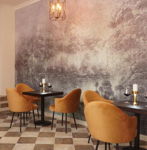 a restaurant with tables and chairs in front of a wall at Hotel Pietryna in Łódź