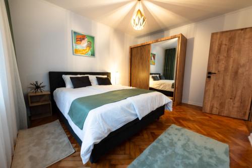 a bedroom with a large bed and a mirror at Fortuna Apartments in Baia Mare