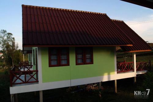 a green and white house with a red roof at Baan Termsuk in Khao Kho