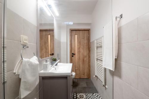 uma casa de banho branca com um lavatório e um espelho em Fortuna Apartments em Baia Mare