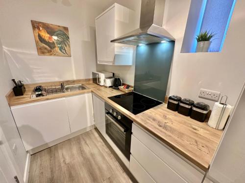 uma cozinha com armários brancos e um forno de fogão preto em Urban Retreat - Close To Town and Beach em Bournemouth