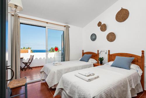 two beds in a room with a view of the ocean at Apartamento Arenal Jardin in Arenal d'en Castell