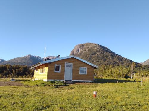 una casa en un campo con montañas en el fondo en Rinconcito de CHABELA en Junín de los Andes