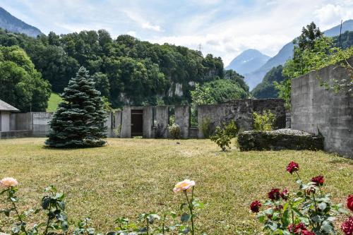 an old building in a field with mountains in the background at Hôtel Restaurant Le Saint-Christophe in Bex