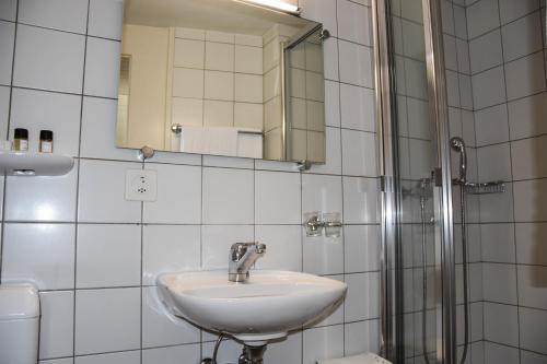 a white bathroom with a sink and a mirror at Hôtel Restaurant Le Saint-Christophe in Bex