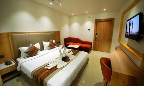 a hotel room with a large bed and a television at FabHotel Prime Surya in Jabalpur