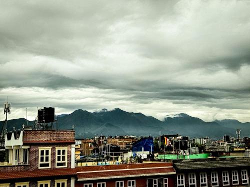 a city under a cloudy sky with mountains in the background at Badri Homes in Pātan