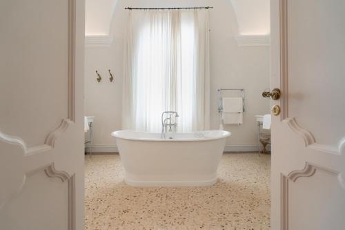 eine weiße Badewanne im Bad mit Fenster in der Unterkunft Palazzo Maritati in Nardò