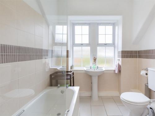 a bathroom with a tub and a toilet and a sink at 5 Bed in Brodick CA016 in Brodick