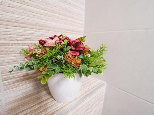 a white vase filled with flowers on a wall at Chaloupka Na Pivovaře Seč in Seč