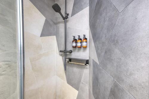 una ducha con cuatro botellas de aceites en una pared en Superbe appartement, hypercentre, 4chambres., en Béziers