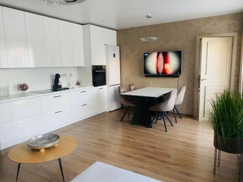 a kitchen with white cabinets and a table with chairs at Gedimino 9 in Marijampolė