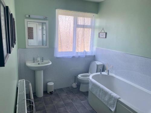 a bathroom with a tub and a toilet and a sink at 3 Bed in Dumfries 77430 in Auldgirth