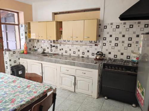 uma cozinha com armários brancos e um fogão preto em Goldenball em Cochabamba