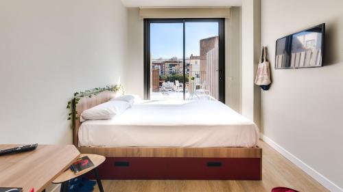 a bedroom with a bed with a window and a desk at Livensa Living Studios - Valencia Viveros in Valencia