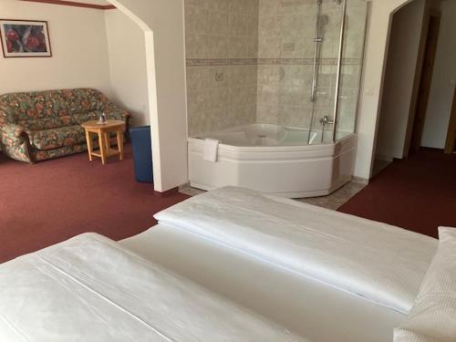 ein Schlafzimmer mit einer Badewanne, einem Bett und einem Sofa in der Unterkunft Walliserhof in Täsch