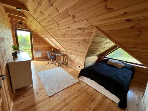 sypialnia z łóżkiem w drewnianym domku w obiekcie Dom Pod Lasem w Rydzewie