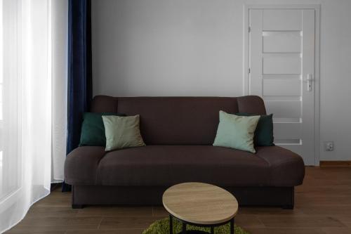 a living room with a brown couch and a table at Apartamenty Cicha - bezpłatny parking in Krynica Zdrój