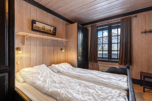 Cama grande en habitación con paredes de madera en Tinden Apartments, en Hemsedal