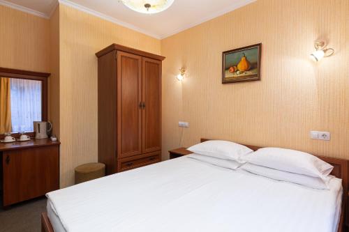 a bedroom with a white bed and a wooden cabinet at Bukovel Hotel in Bukovel