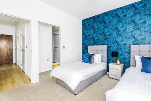 um quarto com 2 camas e uma parede com detalhes em azul em 2 Bedroom Manchester Gem Ancoats em Manchester