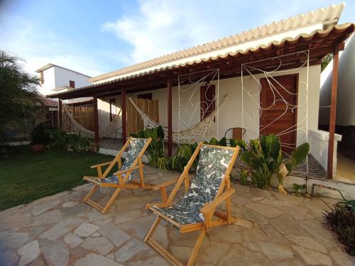 two chairs on a patio in front of a house at Pousada Casa Do Cocotier in São Miguel do Gostoso