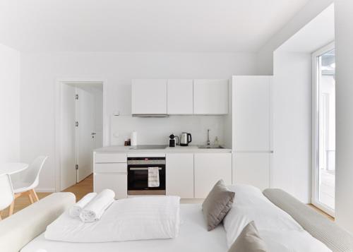 a white kitchen with a large white bed in a room at Stylish & Modern Apartment - Private Garden & Free Parking in Vienna