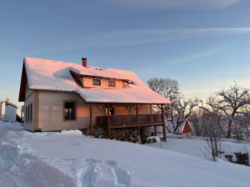 a house with a snow covered roof on top of a pile of snow at U nás ve lhotě - apartmány / celá chalupa in Borotín
