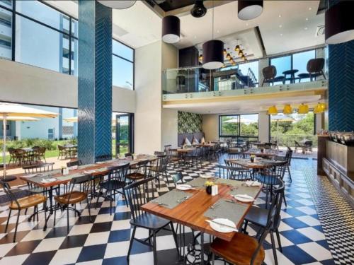 a restaurant with tables and chairs and windows at The Regency Aparthotel in Pretoria