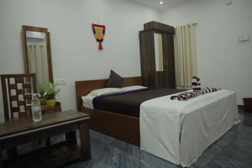 una camera d'albergo con due letti, un tavolo e un mobile da bagno con lavabo. di AARONIC STAY a Varkala