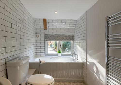 baño con bañera, aseo y ventana en Honeysuckle Cottage - Bramfield, en Bramfield