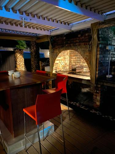 a bar with red chairs and a brick fireplace at Cottonwood Guesthouse Oasis in Bloemfontein