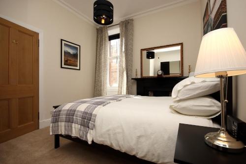 een slaapkamer met een bed met een lamp en een spiegel bij Hamish's Hame Edinburgh Licence No EH 69774 P in Edinburgh