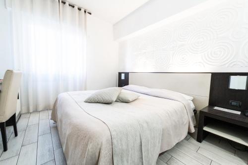 a white bedroom with a bed and a desk at EcoHotel Ristorante Milano in Borgo a Mozzano